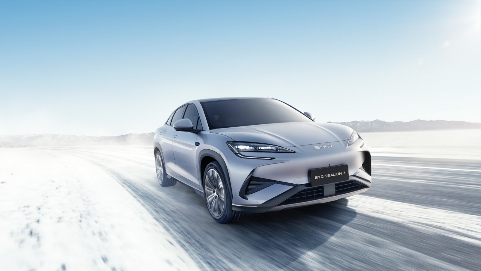 Samochód elektryczny BYD jadący zimą po zaśnieżonej drodze